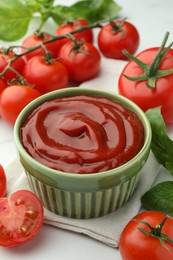 Photo of Bowl of tasty ketchup, tomatoes and basil on white table, closeup