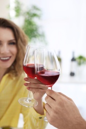 Young couple with glasses of delicious wine indoors