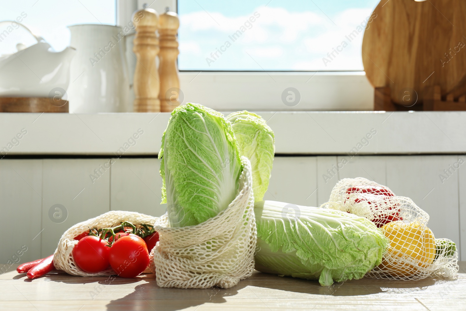 Photo of Fresh Chinese cabbages and other vegetables on light wooden table indoors