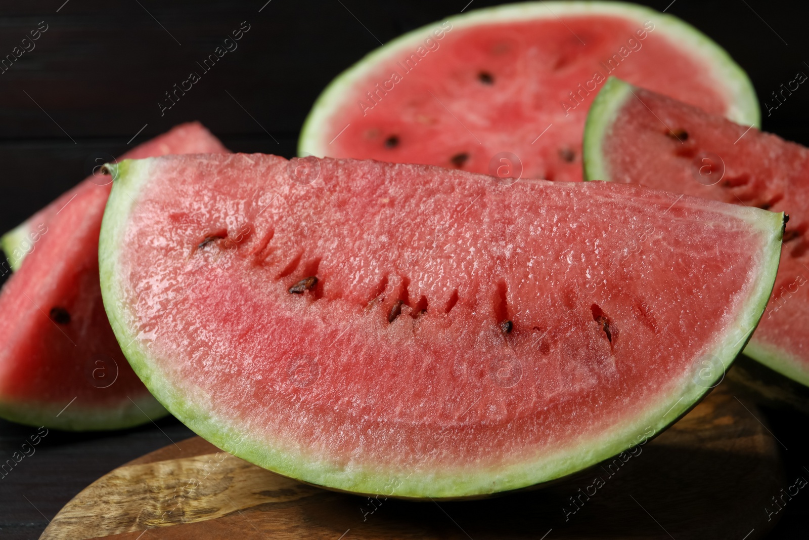 Photo of Slices of tasty ripe watermelon on wooden board, closeup