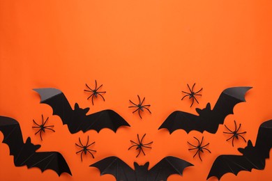 Photo of Flat lay composition with paper bats and spiders on orange background, space for text. Halloween celebration