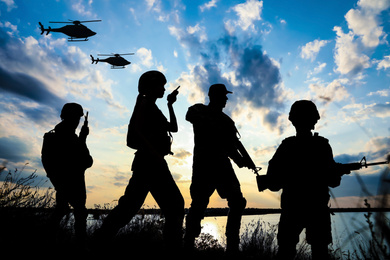 Silhouettes of soldiers with assault rifles and military helicopters patrolling outdoors