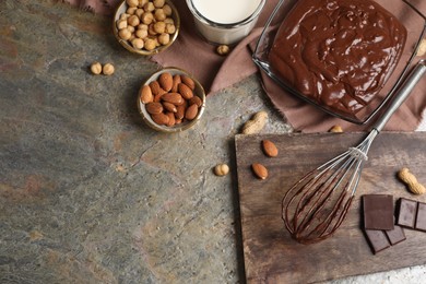 Bowl of chocolate cream, whisk and ingredients on textured table, flat lay. Space for text