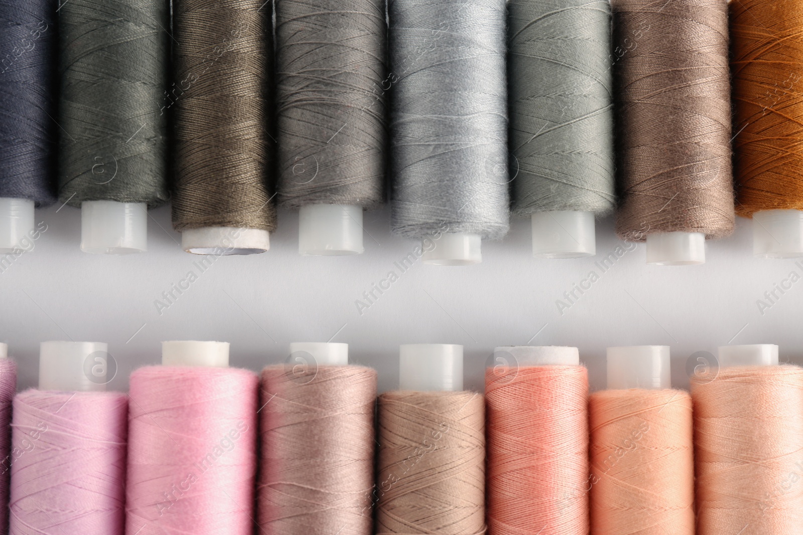 Photo of Set of colorful sewing threads on white background, flat lay