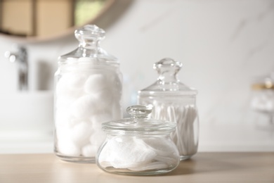 Photo of Cotton balls, swabs and pads on wooden table against blurred background
