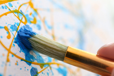 Photo of Artist painting on canvas with brush, closeup