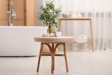 Photo of Spa products, burning candles and plumeria flower on small table in bathroom