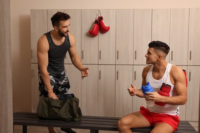 Photo of Handsome athletic men talking in locker room