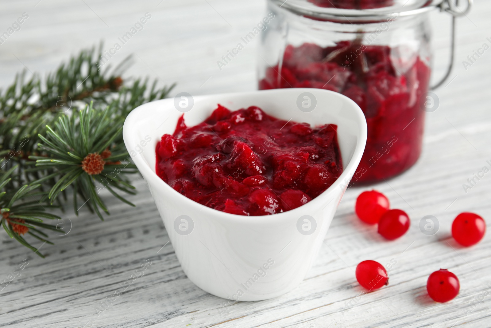Photo of Bowl of tasty cranberry sauce on table, closeup