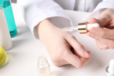 Photo of Dermatologist testing essential oil at white table, selective focus