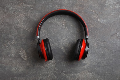 Stylish modern headphones on concrete background, top view