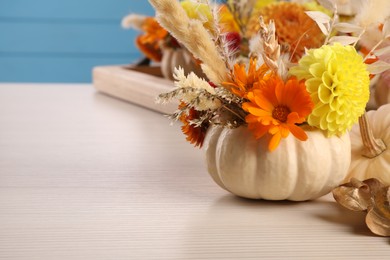 Photo of Small pumpkin with autumn bouquet on light wooden table, closeup. Space for text