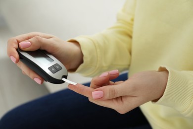 Diabetes. Woman checking blood sugar level with glucometer at home, closeup