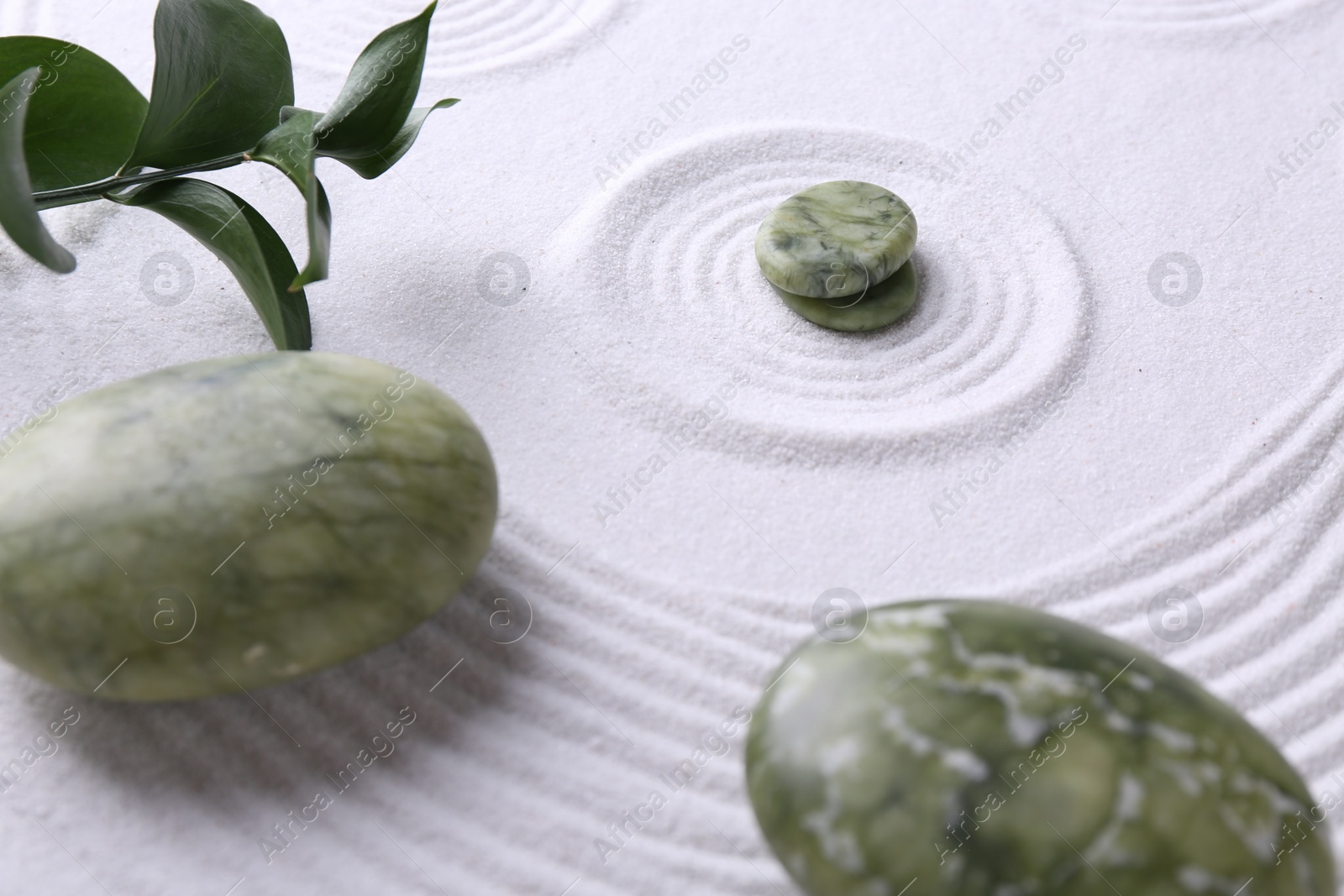 Photo of Zen concept. Stones, leaves and pattern on white sand, closeup