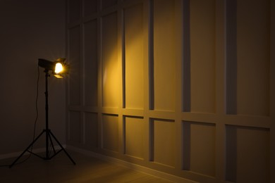 Photo of Bright yellow spotlight near wall indoors, space for text