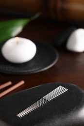 Photo of Acupuncture needles and spa stone on table. Space for text