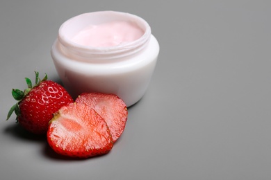 Photo of Jar of body cream and strawberries on grey background. Space for text