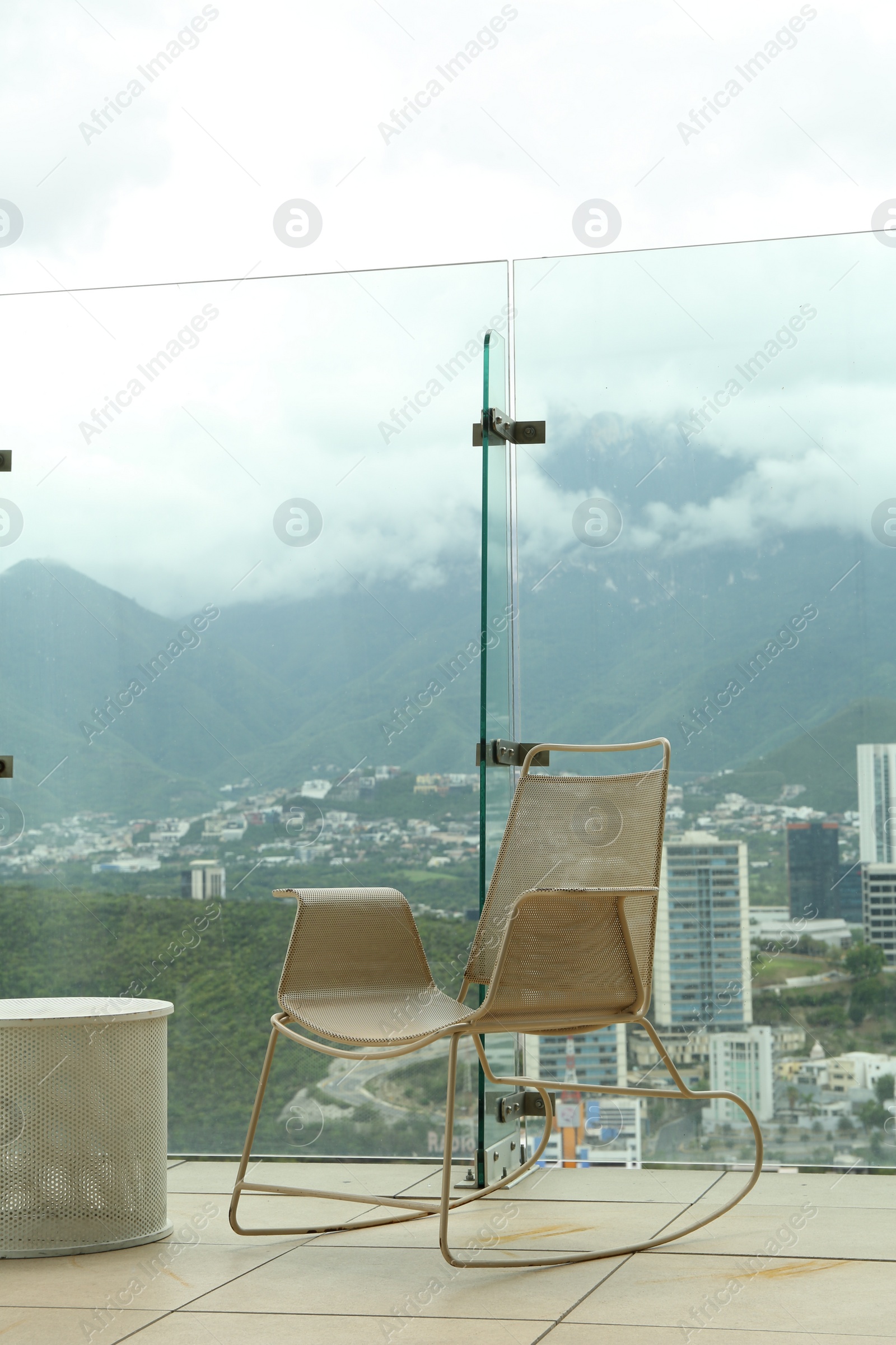 Photo of Coffee table and rocking chair against picturesque landscape of city in cafe