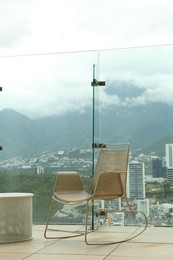 Photo of Coffee table and rocking chair against picturesque landscape of city in cafe