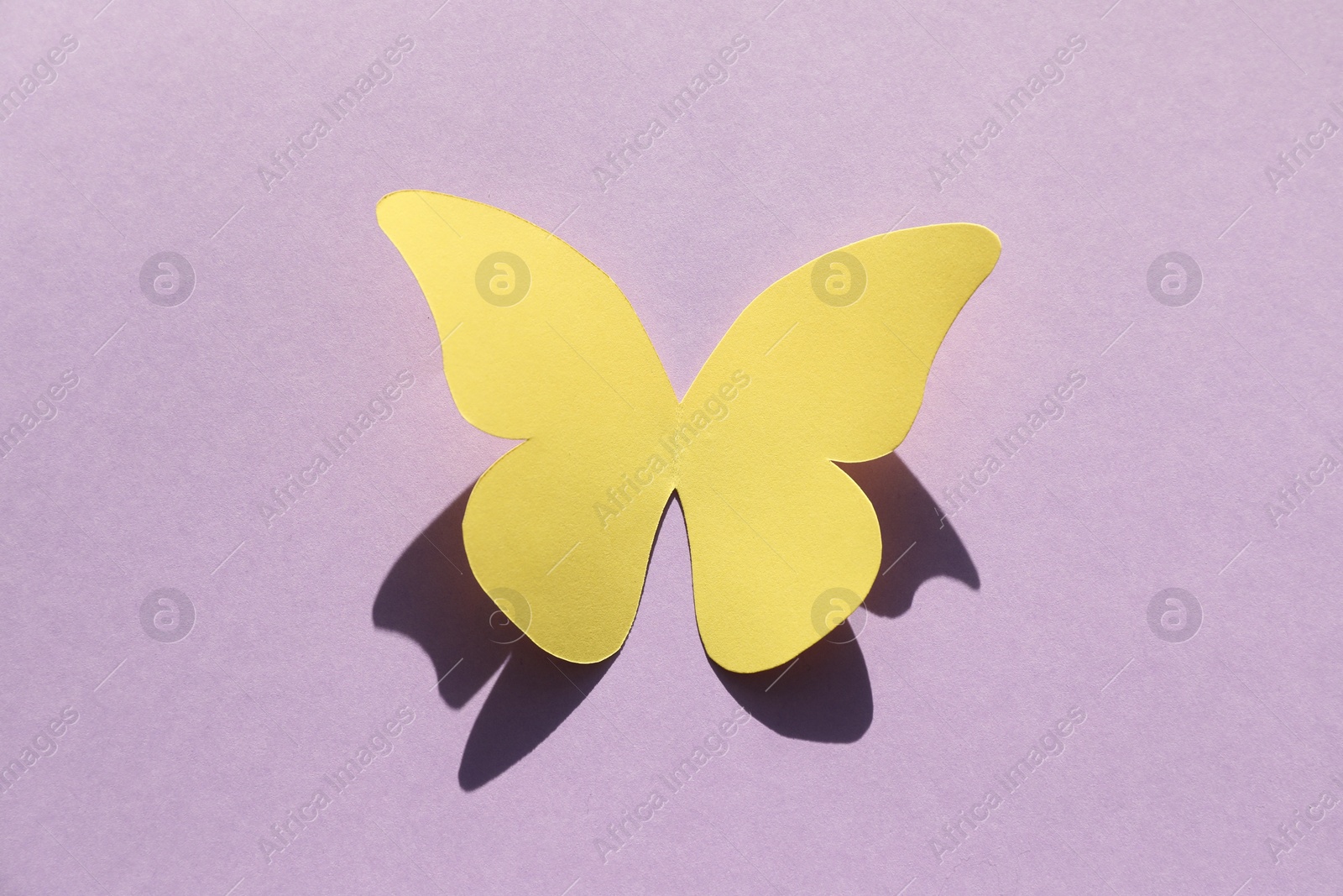 Photo of Yellow paper butterfly on violet background, top view