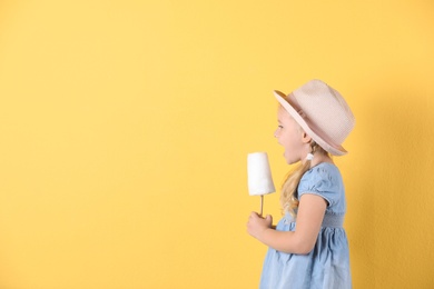 Photo of Cute little girl with cotton candy on color background. Space for text