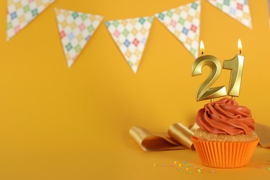 Photo of Coming of age party - 21th birthday. Delicious cupcake with number shaped candles on orange background, space for text