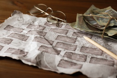 Photo of Paper with family tree template, pencil, photos and glasses on wooden table, closeup
