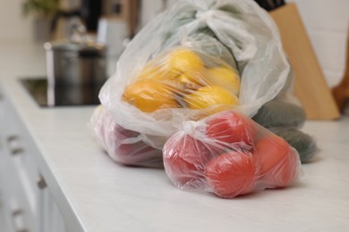 Plastic bags with different fresh products on white countertop in kitchen