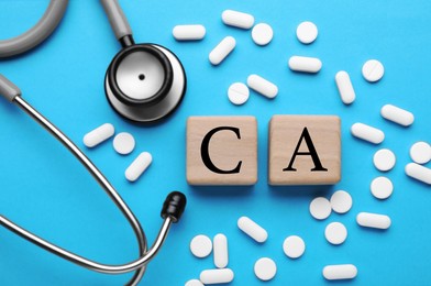 Stethoscope, pills and calcium symbol made of wooden cubes with letters on light blue background, flat lay