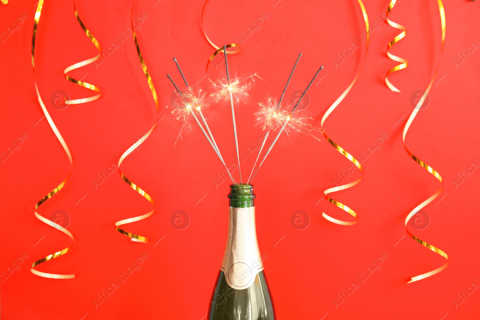 Photo of Creative composition with bottle of champagne and sparklers on color background