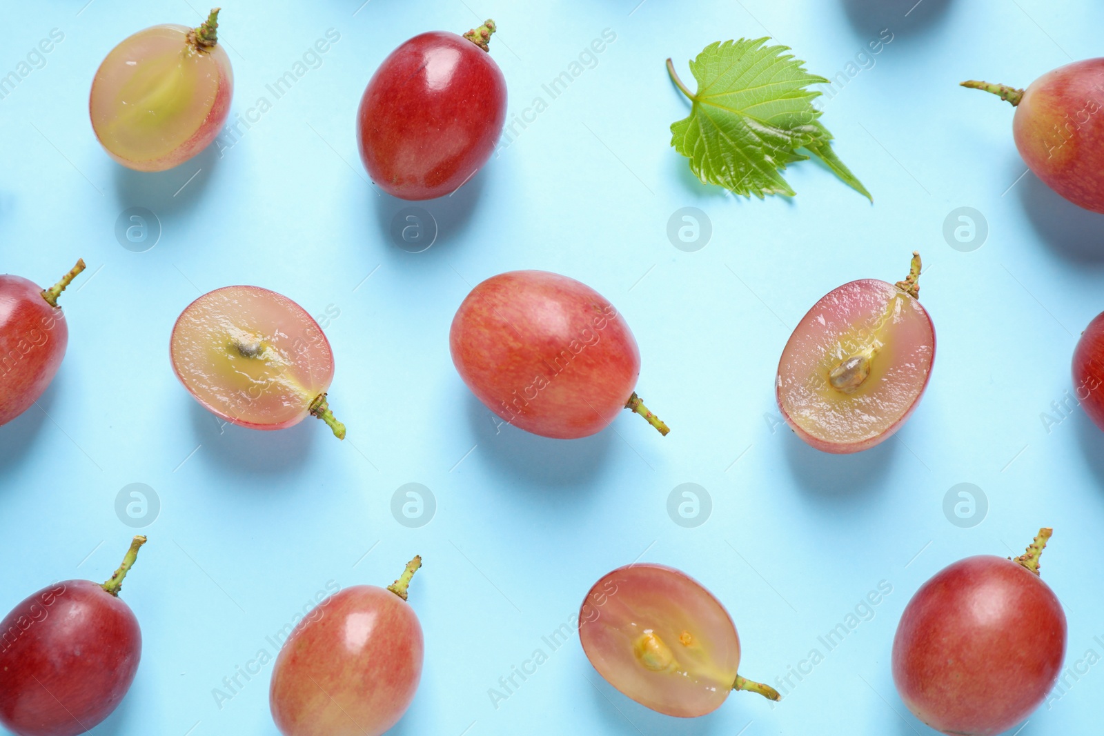 Photo of Flat lay composition with fresh ripe juicy grapes on light blue background