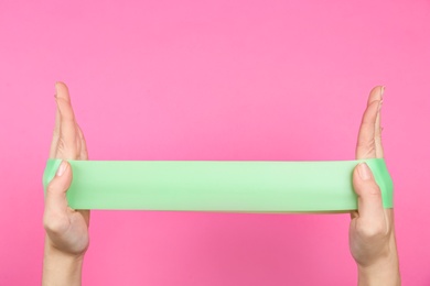 Woman with fitness elastic band on pink background, closeup