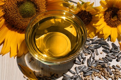 Photo of Sunflower oil in bowl and seeds on wooden table