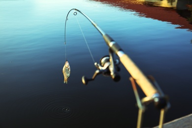 Photo of Fishing rod with caught fish at lake on sunny day