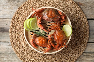 Photo of Delicious boiled crabs with lime and dill in bamboo steamer on wooden table, top view