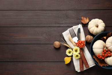 Festive table setting with autumn decor and space for text on wooden background, flat lay. Thanksgiving Day celebration