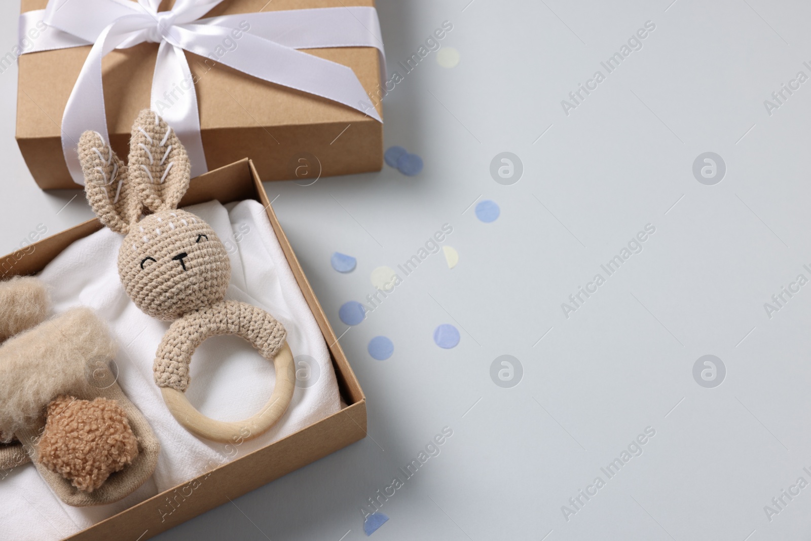 Photo of Different baby accessories in box and confetti on light grey background, flat lay. Space for text