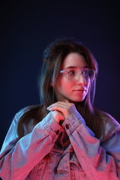 Portrait of beautiful young woman in glasses on color background