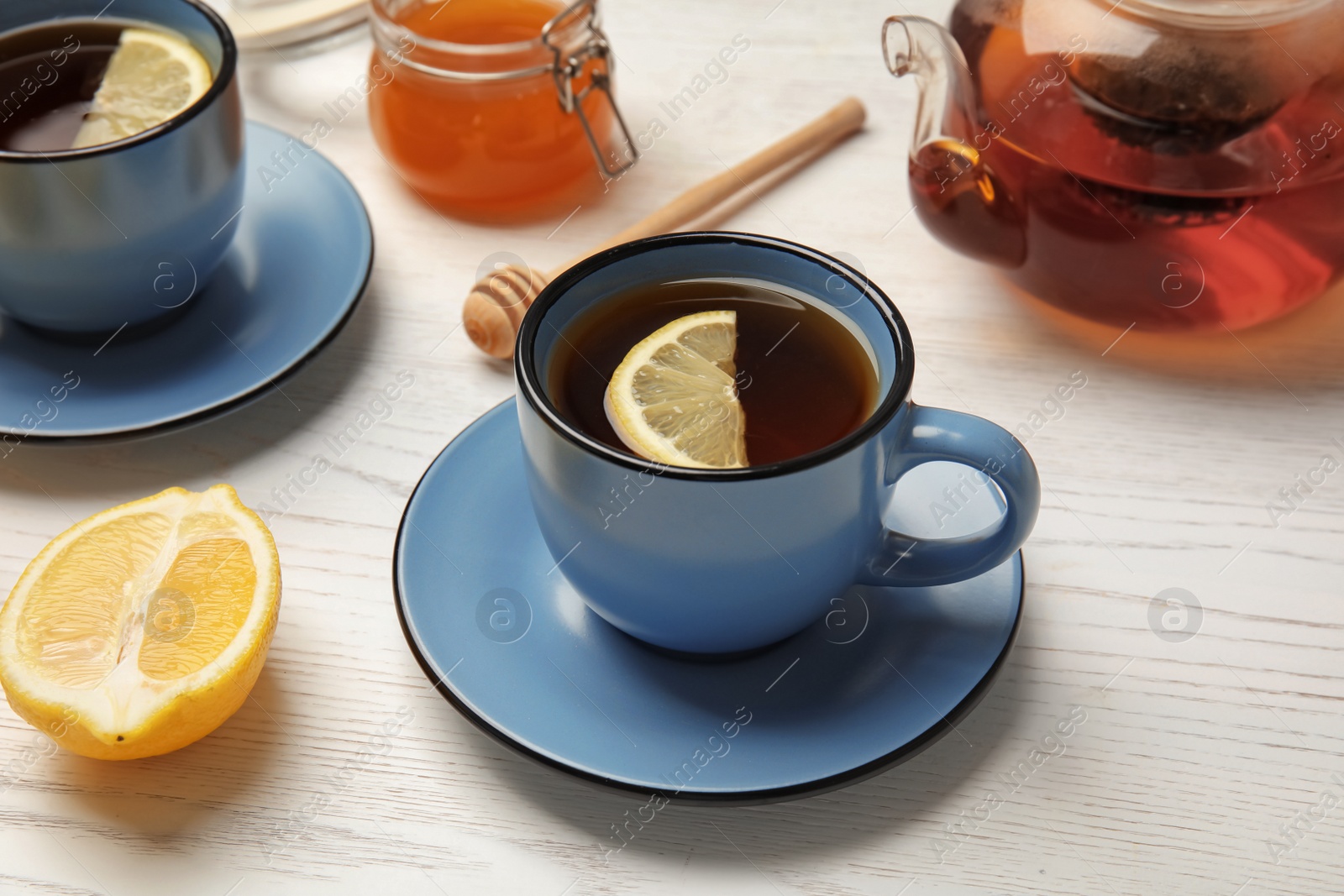 Photo of Cup with black tea and lemon on table