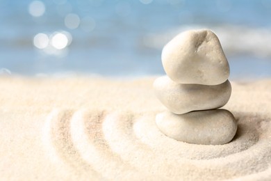 Image of Stack of white stones on sand with pattern, space for text. Zen, meditation, harmony