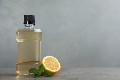 Photo of Mouthwash, mint and lemon on grey table, space for text