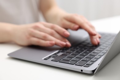 Photo of E-learning. Woman using laptop at white table indoors, closeup