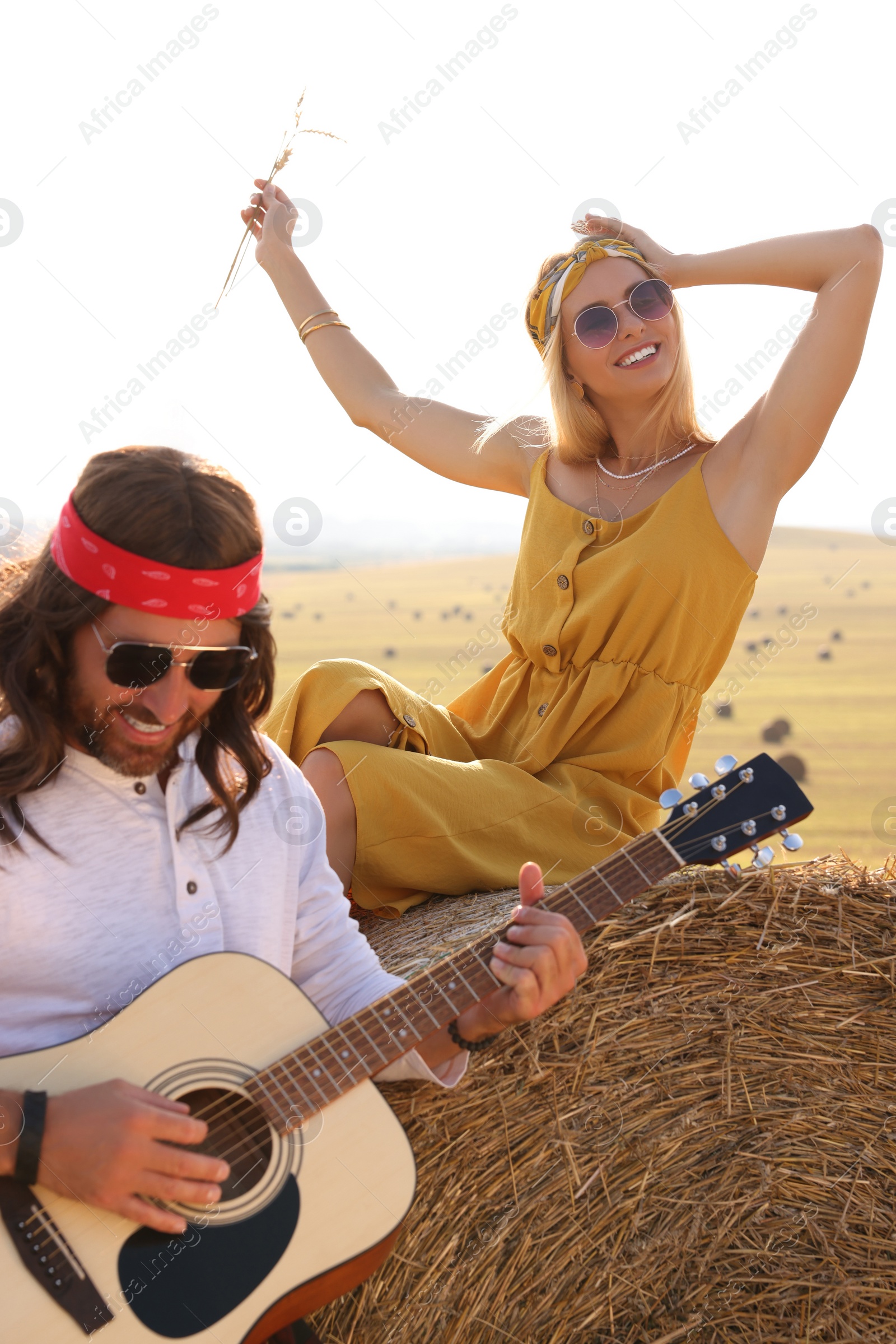 Photo of Beautiful hippie woman listening to her friend playing guitar in field