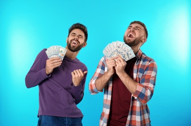 Photo of Happy young men with money on color background