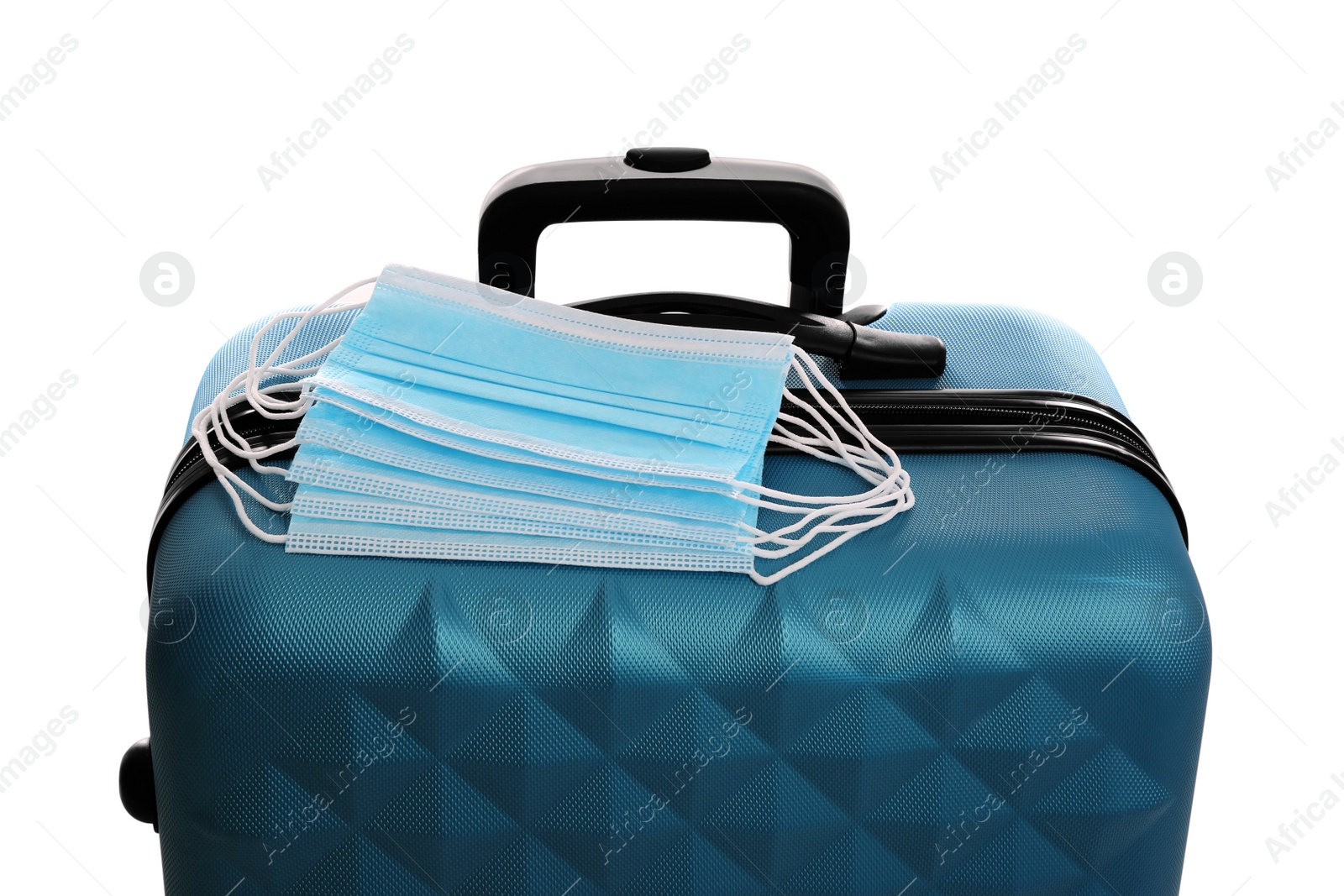 Photo of Stylish blue suitcase and protective masks on white background. Travelling during coronavirus pandemic