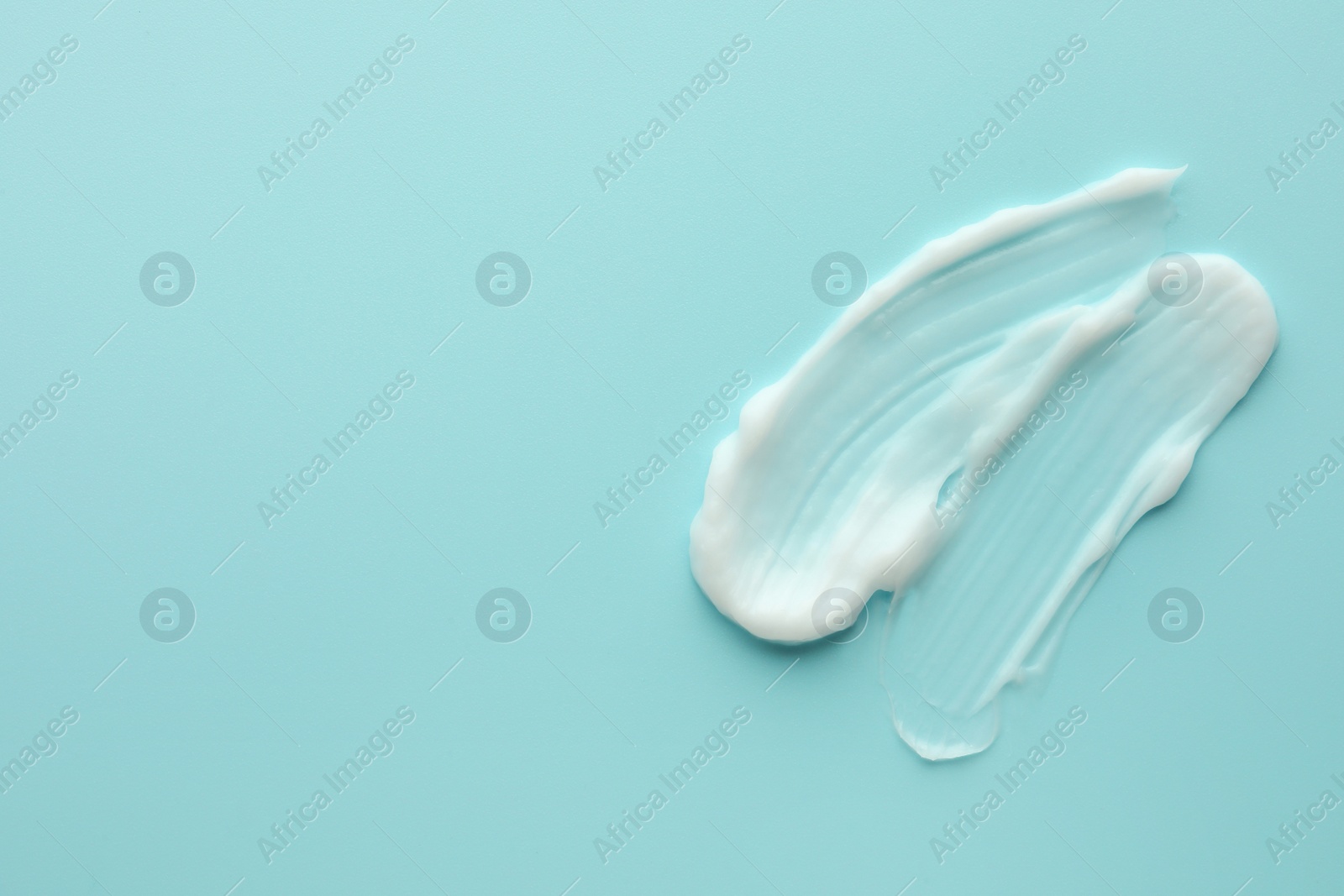 Photo of Samples of face cream on light blue background, top view. Space for text