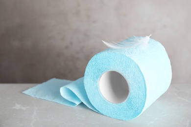 Photo of Toilet paper roll with feather on grey background