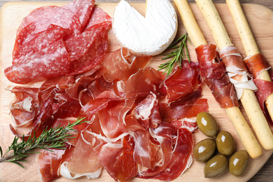 Photo of Tasty prosciutto served on wooden table, flat lay