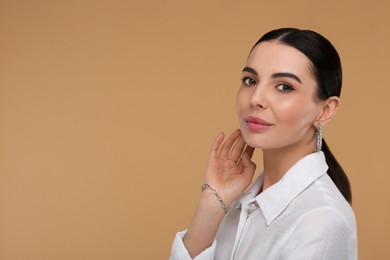 Photo of Beautiful young woman with elegant jewelry on beige background. Space for text