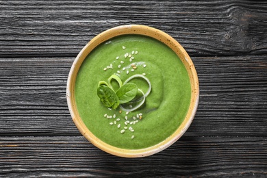 Photo of Fresh vegetable detox soup made of spinach in dish on wooden background, top view